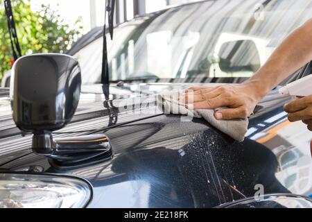 Il personale addetto alla pulizia utilizza una vernice e un panno in microfibra per pulire il corpo di un'auto, un concetto per l'industria della cura dell'automobile. Foto Stock