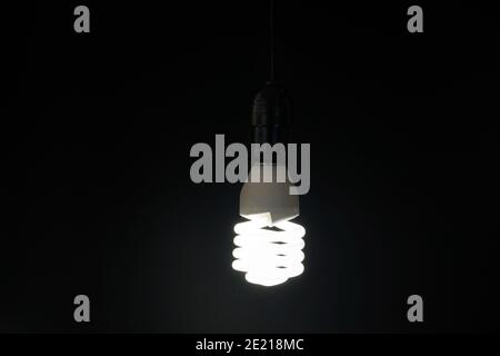 La lampada fluorescente si accoschiera con una luce bianca sull'oscurità e con uno spazio per la copia. Foto Stock