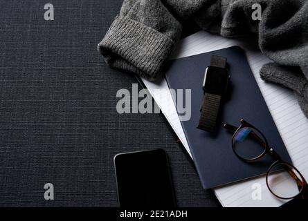 Flat Lay Lifestyle Shot con Jumper Smartwatch notebook e cellulare Telefono su sfondo nero Foto Stock