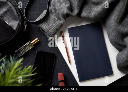 Flat Lay Lifestyle Shot con jumper Cosmetics notebook e borsa Su sfondo nero Foto Stock