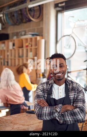Ritratto del proprietario di piccola impresa in officina assemblaggio realizzato a mano Biciclette di bambù sostenibili Foto Stock