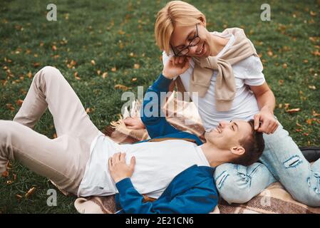 Coppia gay amorevole che ha date romantiche all'aperto. Due bei uomini seduti insieme sulla coperta nel parco. Concetto LGBT. Foto Stock