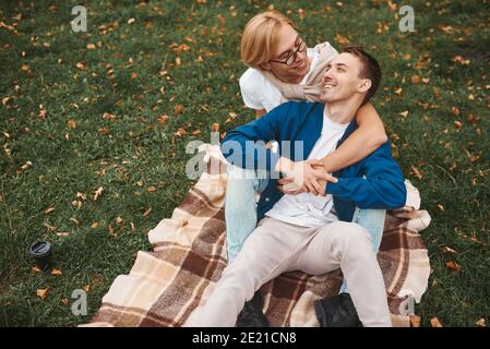 Coppia gay amorevole che ha date romantiche all'aperto. Due bei uomini seduti insieme sulla coperta nel parco e abbracciando. Concetto LGBT. Foto Stock