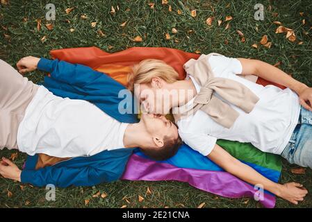 Coppia gay amorevole che ha date romantiche all'aperto. Due bei uomini che giacciono insieme sulla bandiera dell'orgoglio di LGBT. Foto Stock