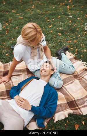 Coppia gay amorevole che ha date romantiche all'aperto. Due bei uomini seduti insieme sulla coperta nel parco. Concetto LGBT. Foto Stock