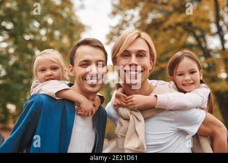 Due genitori gay con le loro figlie adottivi che camminano insieme nel parco. Buon concetto di famiglia LGBT. Foto Stock