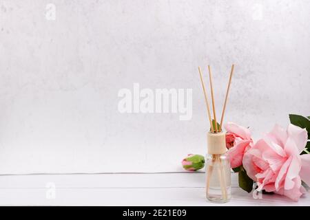 deodorante per ambienti su sfondo bianco in legno con rose rosa, spazio copia Foto Stock