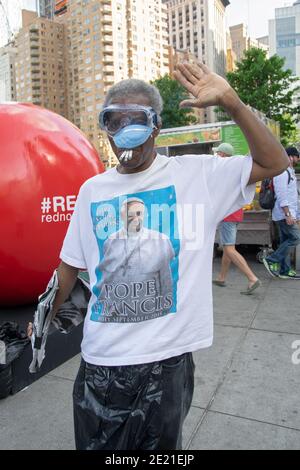 Un uomo che indossa una camicia Papa Francesco, occhiali e maschera e fumare 3 sigarette. Vicino a Union Square Park a New York City. Foto Stock