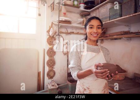 Ritratto di vasaio femminile che indossa grembiule di tenuta di Clay In Ceramica Studio Foto Stock