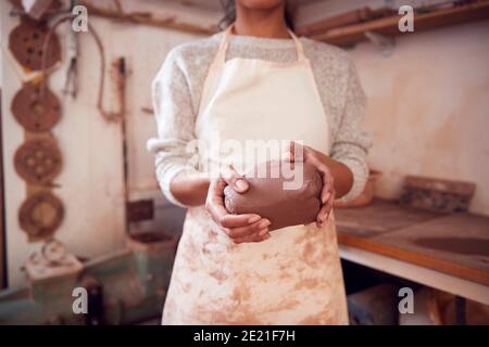 Primo piano di femmina Potter che indossa grembiule di tenuta di Clay in Ceramica Studio Foto Stock