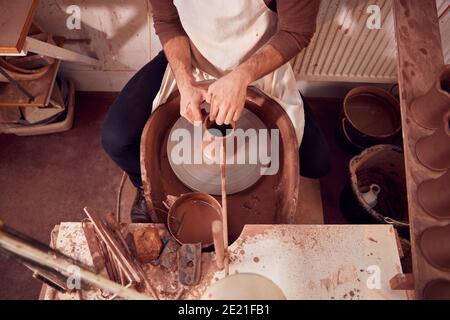 Primo piano della argilla di formatura del vasaio maschio per il piatto Ruota in ceramica in Ceramica Studio Foto Stock