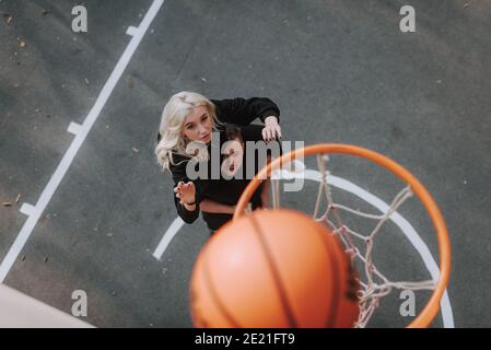 Vista dall'alto di un giovane uomo e di una donna che indossano un abbigliamento sportivo nero e giocare a pallacanestro all'aperto Foto Stock