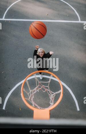 Vista dall'alto di una giovane donna sorridente che si allenava all'aperto sul basket campo Foto Stock