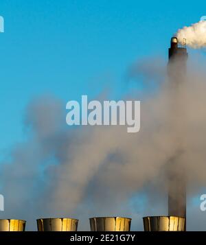 Pile di fumo industriali che emettono vapore e fumo su un cielo blu chiaro. Foto Stock