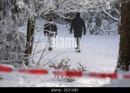 Rusel, Germania. 11 Gennaio 2021. Gli escursionisti camminano dietro un nastro di barriera sulla montagna Rusel nel quartiere di Deggendorf. Numerose contee e città indipendenti in Baviera vogliono chiudere i loro confini a escursionisti di giorno. Credit: Armin Weigel/dpa/Alamy Live News Foto Stock