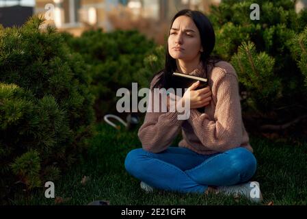 Giovane donna in abbigliamento casual trascorrere il tempo da sola nel non tenere il notebook Foto Stock