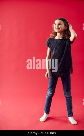Full Length Ritratto di ragazza contro Red Studio sfondo sorridente Alla fotocamera Foto Stock