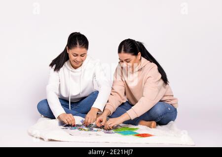 Le ragazze gemelle raccolgono entusiasticamente un puzzle sul pavimento. Un passatempo interessante. Foto Stock
