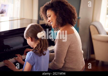 Giovane ragazza imparare a suonare piano avendo lezione da femmina Insegnante Foto Stock