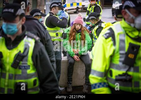 Un protestante è circondato dalla polizia durante una protesta scozzese contro Lockdown al di fuori del Parlamento scozzese a Edimburgo. In base alle attuali normative sul coronavirus che riguardano la Scozia continentale, le persone non possono lasciare la casa per scopi diversi da quelli essenziali, il che significa che le marce e le proteste sono vietate. Foto Stock