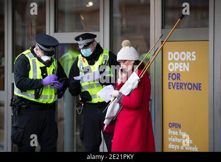 Protestante e polizia durante una protesta contro Lockdown al di fuori del Parlamento scozzese a Edimburgo. In base alle attuali normative sul coronavirus che riguardano la Scozia continentale, le persone non possono lasciare la casa per scopi diversi da quelli essenziali, il che significa che le marce e le proteste sono vietate. Foto Stock