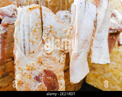 Carne di maiale cruda stagionata e impiccata per il processo di fumo Foto Stock