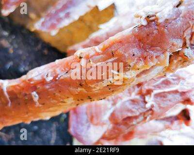 Carne di maiale cruda stagionata e impiccata per il processo di fumo Foto Stock