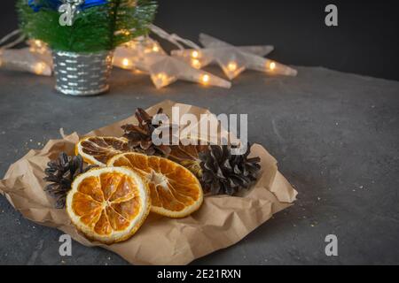 Composizione natalizia su tavolo scuro. Fette di arancia e limone essiccate, coni di abete. Tema di Natale, fuoco selettivo. Foto Stock