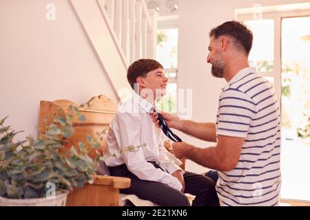 Padre che aiuta Son a legare Necktie prima che lasci la casa Per il primo giorno a High School Foto Stock