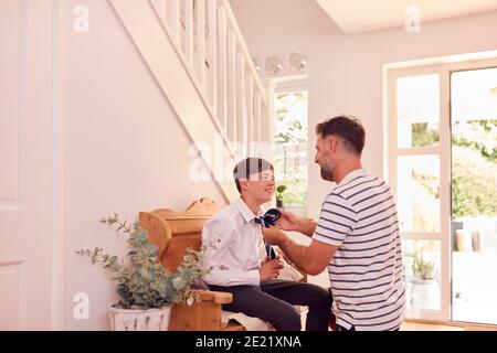 Padre che aiuta Son a legare Necktie prima che lasci la casa Per il primo giorno a High School Foto Stock
