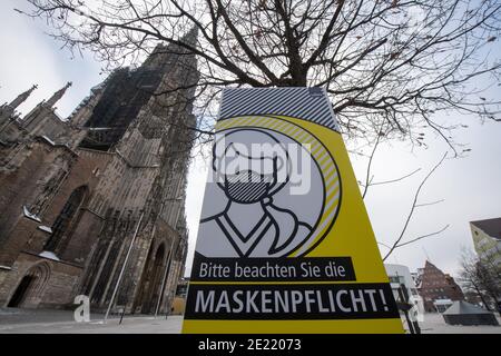 11 gennaio 2021, Baden-Wuerttemberg, Ulm: Un cartello di fronte alla Cattedrale di Ulm con la torre della chiesa più alta del mondo indica che le maschere sono obbligatorie. Foto: Stefan Puchner/dpa Foto Stock
