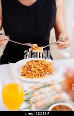 Immagine ravvicinata di una donna che gusterai deliziosi spaghetti bolognesi durante le feste cena a casa Foto Stock