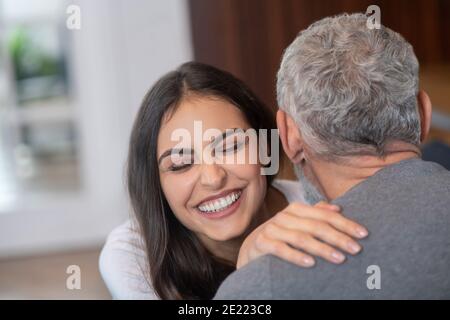 Giovane donna dai capelli lunghi che abbracciava il suo sposo dai capelli grigi Foto Stock