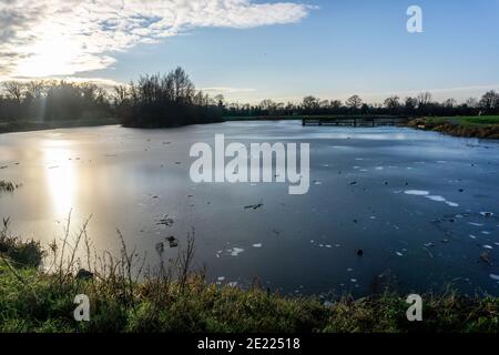Il lago di pesca congelato nel parco di Corcagh, Clondalkin, Dublino, Irlanda in un giorno di gennaio amaramente freddo. Foto Stock