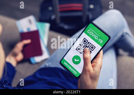 persona vaccinata che usa l'app per passaporto sanitario digitale sul telefono cellulare per viaggiare durante la pandemia di covid-19 Foto Stock