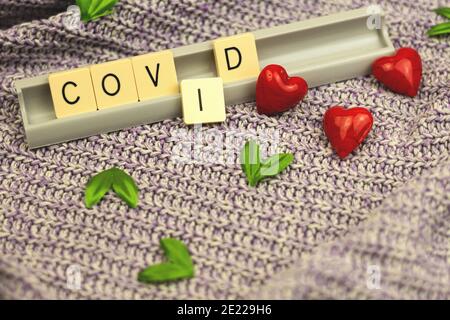 San Valentino 2021 concept composizione con cuore rosso e parola COVID-19 su sfondo lavorato a maglia, biglietto d'auguri foto Foto Stock