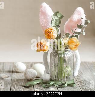 Un bouquet di fiori in vaso di vetro con elementi decorativi. Concetto di vacanza di Pasqua. Foto Stock