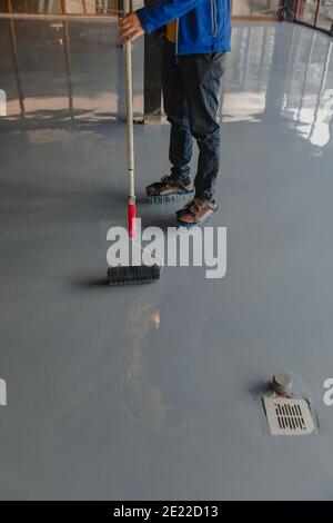 L'operatore applica la resina epossidica grigia al nuovo pavimento Foto Stock