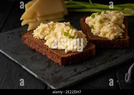 Uova strapazzate con cipolla verde con pane senza glutine tavolo nero Foto Stock
