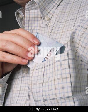 Uomo che mette la nota euro in tasca Foto Stock