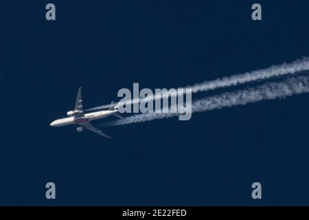 Eindhoven, Paesi Bassi. 09 gennaio 2021. Un velivolo Emirates Boeing 777 è visto volare a 40.000 piedi nel cielo blu sopra i Paesi Bassi. Il velivolo sorvolante crea contrasti, le linee bianche di vapore di condensazione. L'aereo parte da Dubai DXB UAE verso l'Inghilterra, Regno Unito. Credit: SOPA Images Limited/Alamy Live News Foto Stock