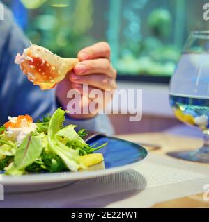 Donna tiene un artiglio di granchio in mano ad un ristorante di pesce. Cena a base di pesce in un'accogliente caffetteria Foto Stock