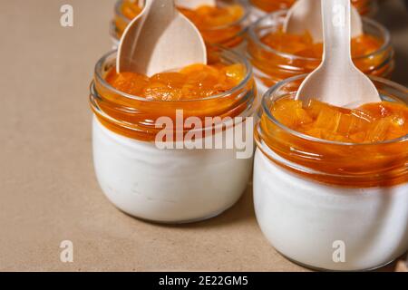 Frullato di panna montata e persimmon in un vaso di vetro. Cucchiai in legno in vasi. Foto Stock