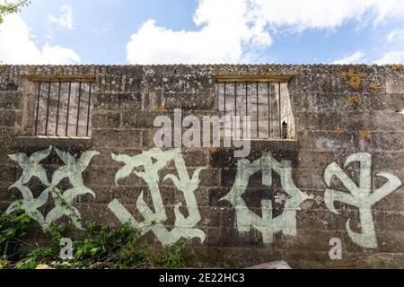 Abbandonato edificio derelict in un campo di pecore, l'ex guerra mondiale Richborough una prigione, centro di detenzione. Strani graffiti alieni moderni sulla parete. Foto Stock