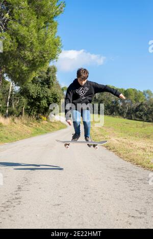 Action shot di un giovane skater teen maschio che salta in alto su una strada in collina Foto Stock