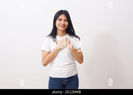 La donna fedele chiude gli occhi e tiene le mani sul petto vicino al cuore, mostra la sua gentilezza o il suo favore, esprime emozioni sincere, essere gentili e affini Foto Stock