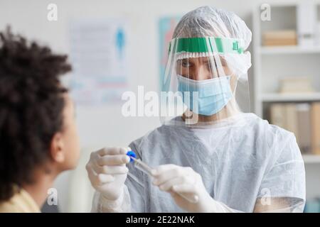 Vita in su ritratto del medico maschio che indossa l'attrezzatura protettiva completa che fa il test del tampone covid in clinica, spazio di copia Foto Stock