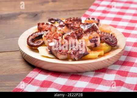 Pulpo a la gallega, polpo galiziano con patate paprika, sale e olio d'oliva. Tipica tapa galiziana spagnola, su una tradizionale piastra di legno. Tipico. Foto Stock