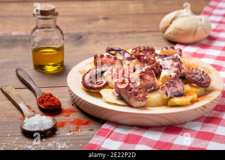 Pulpo a la gallega, polpo galiziano con patate paprika, sale e olio d'oliva. Tipica tapa galiziana spagnola, su una tradizionale piastra di legno. Tipico. Foto Stock