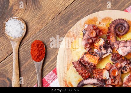 Pulpo a la gallega, polpo galiziano con patate paprika, sale e olio d'oliva. Tipica tapa galiziana spagnola, su una tradizionale piastra di legno. Tipico Foto Stock